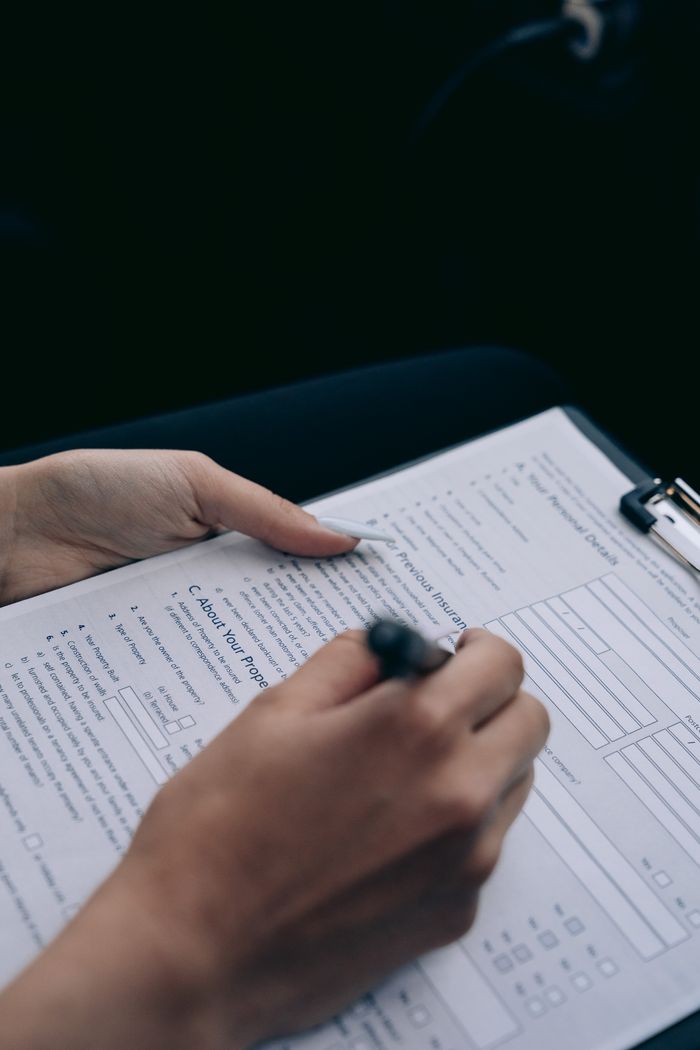 A person's hand writing on a form attached to a clipboard, highlighting data entry.